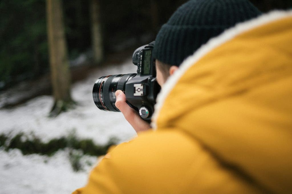 creative photographer uses a specialized lens on his camera in the snow