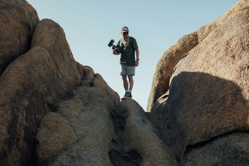 man with a specialized lens stands on a cliff