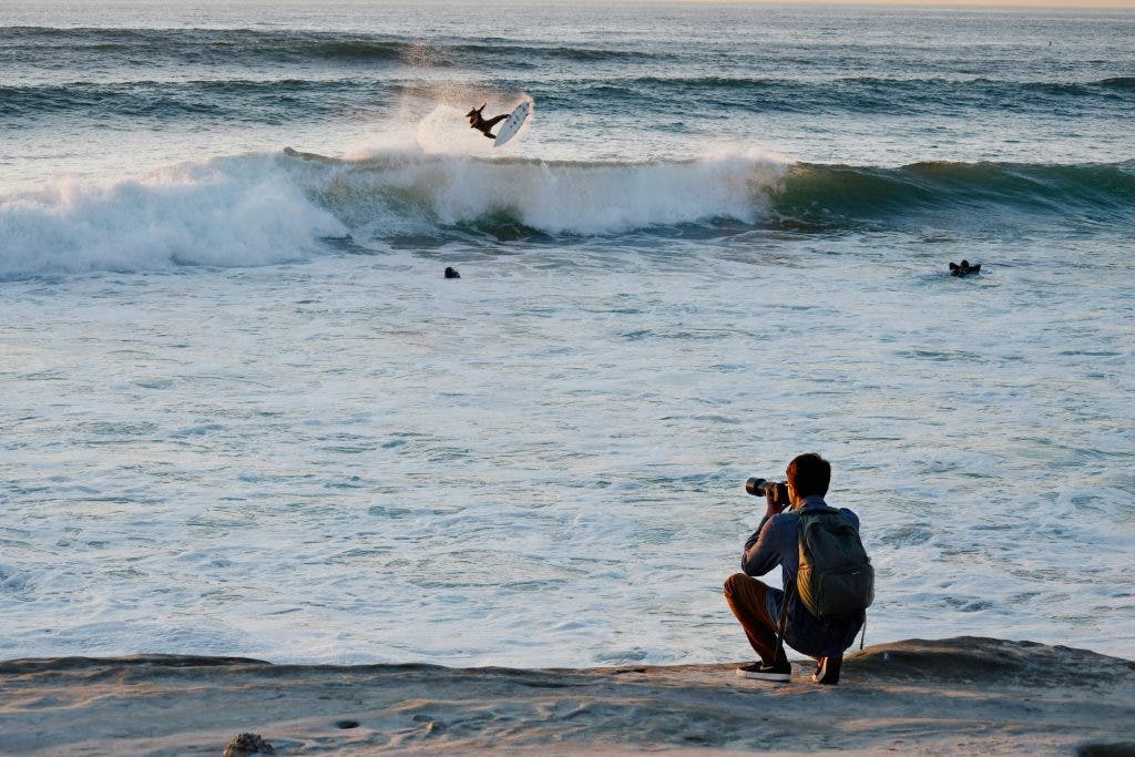sports photographer uses zoom lens to take pictures of a surfer