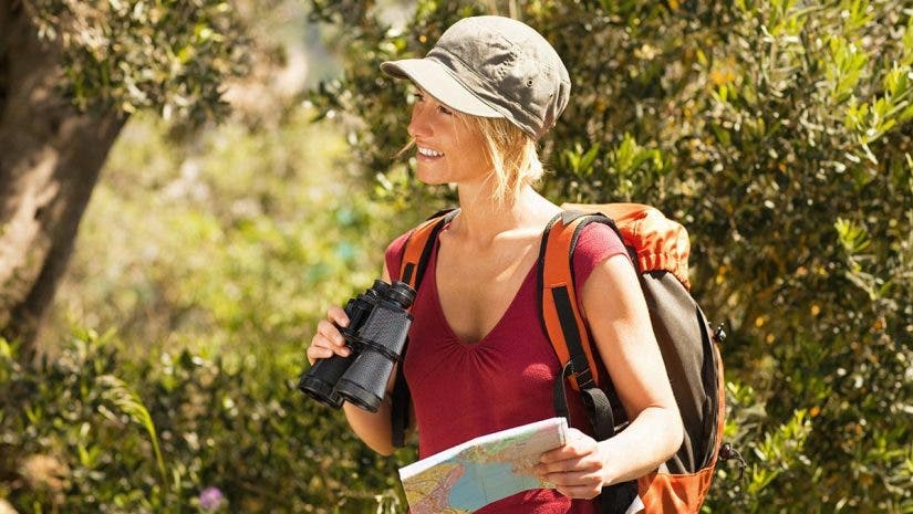 outdoors adventure - aunt- woman hiking and holding binoculars and map.