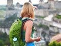 Woman tourist with green backpack makes a photo of an old castle. vacation and summer trip