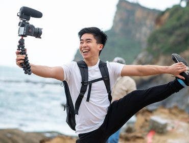 Vlogger holds and smile with his camera