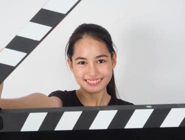 Young woman - Aspiring filmmaker -holding black clapper board or movie slate or clapperboard .it use in video production ,film, movie,cinema industry on white background.