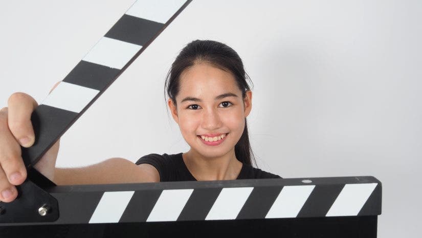Young woman - Aspiring filmmaker -holding black clapper board or movie slate or clapperboard .it use in video production ,film, movie,cinema industry on white background.