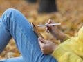 Young woman model sitting with tablet iPad Pro 2021 and painting with pencil stylus in autumn park with yellow foliage maple leaves.