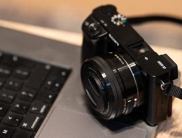 Sony Alpha camera and lens sitting MacBook
