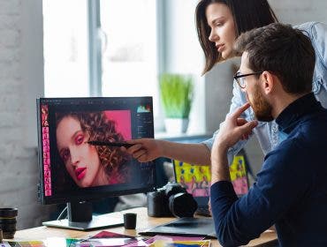 Professionals - photographer and retoucher. Retouching images on a graphics tablet. Teamwork in a professional photo studio.