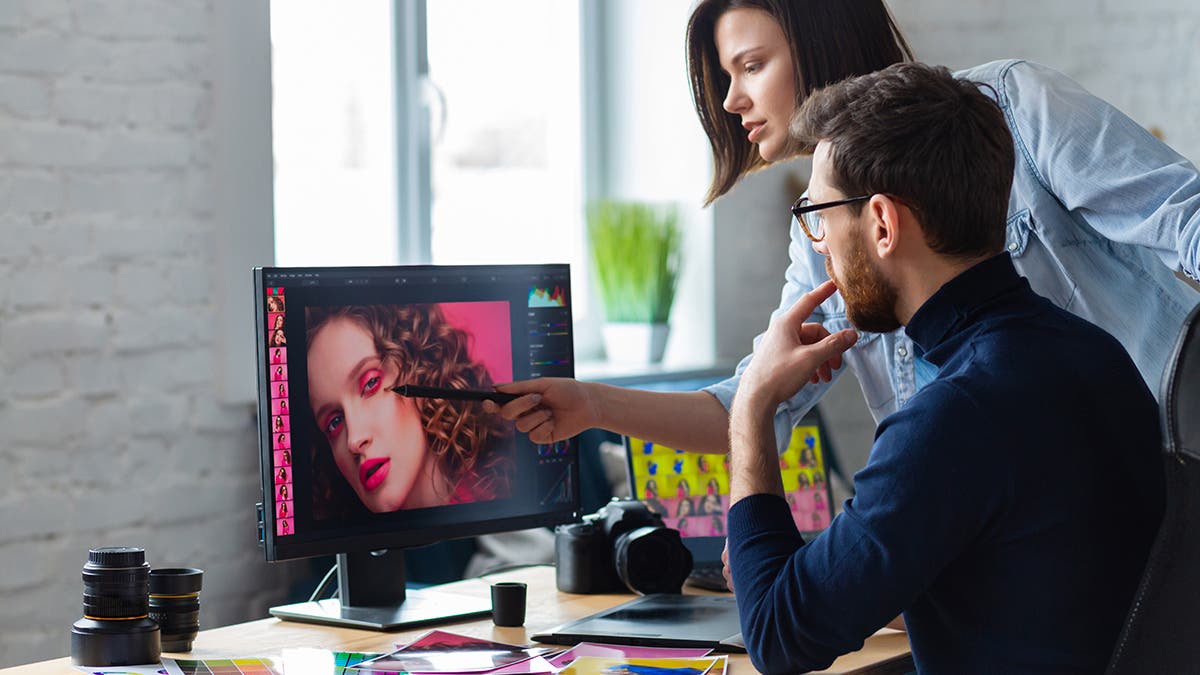 Professionals - photographer and retoucher. Retouching images on a graphics tablet. Teamwork in a professional photo studio.