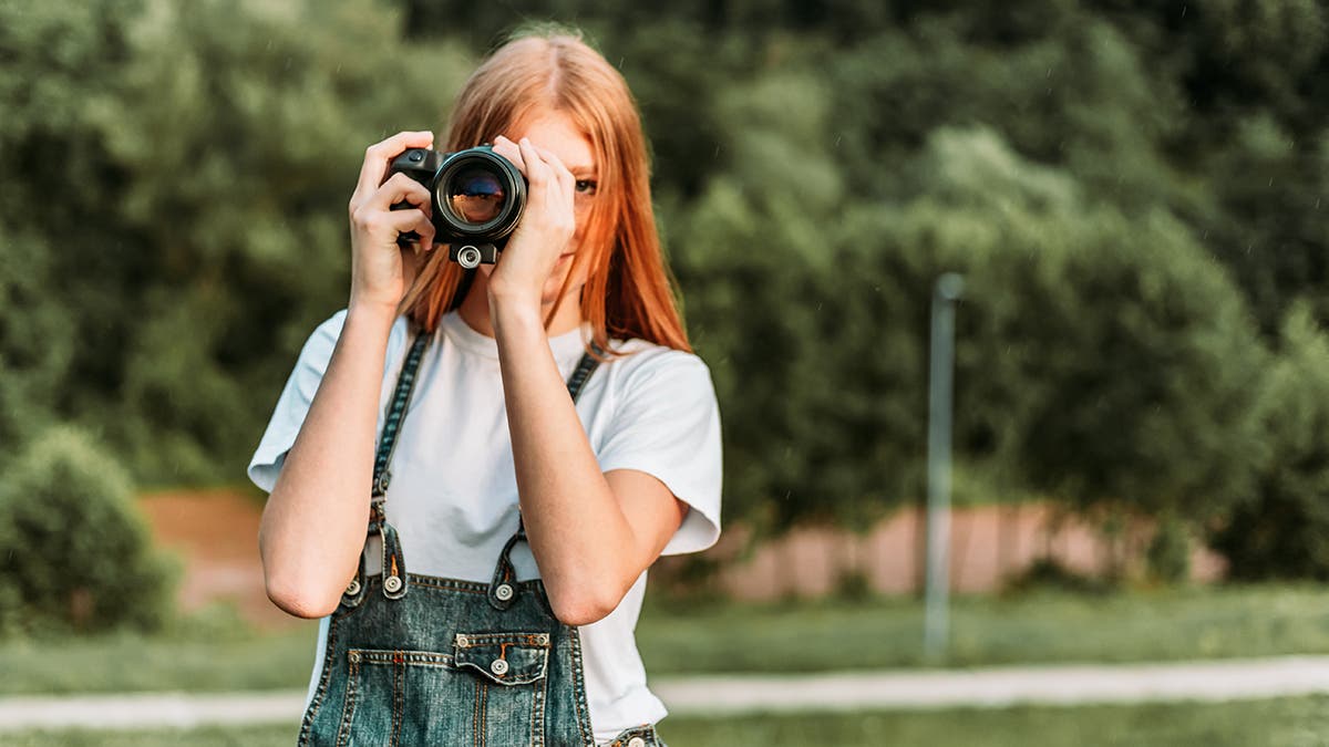 Ginger teen, girl taking photos with camera.