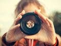 Young woman looking through camera lens