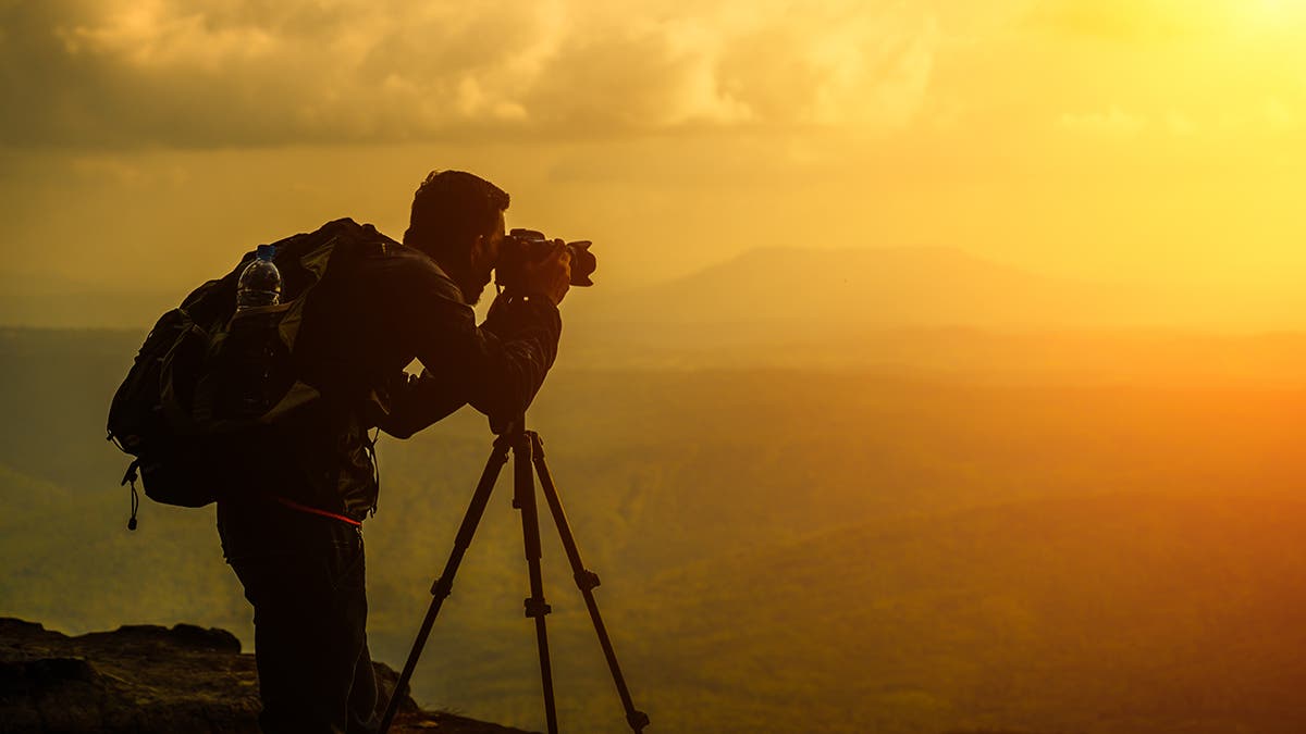 A male photographer travels and shoots landscapes at sunset Landscape photography gear