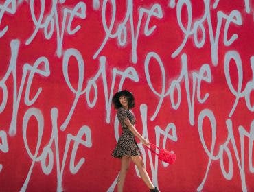 a woman walking across a wall with the word "love" on it