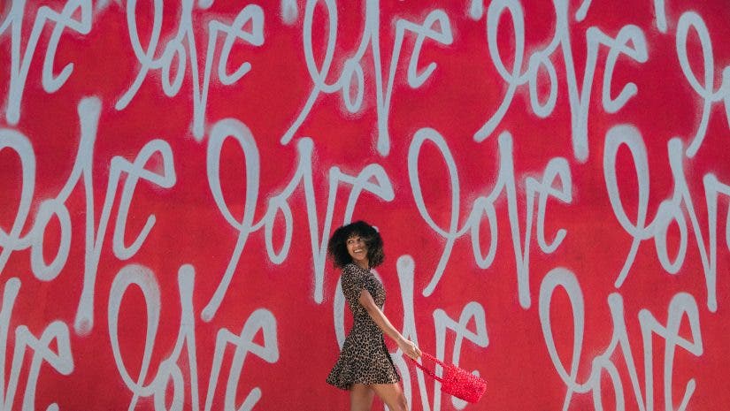 a woman walking across a wall with the word "love" on it