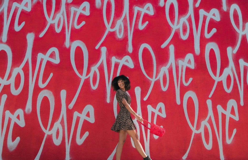 a woman walking across a wall with the word "love" on it