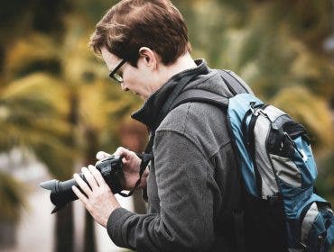 a man tweaking his camera settings while shooting in public