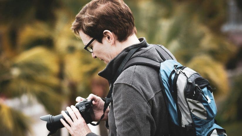 a man tweaking his camera settings while shooting in public