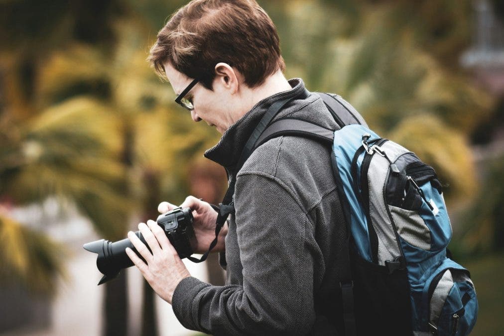 a man tweaking his camera settings while shooting in public