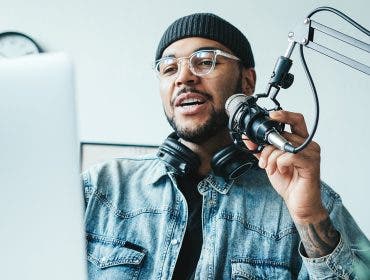 Handsome mixed race man streaming his audio podcast at small and cozy home broadcast studio