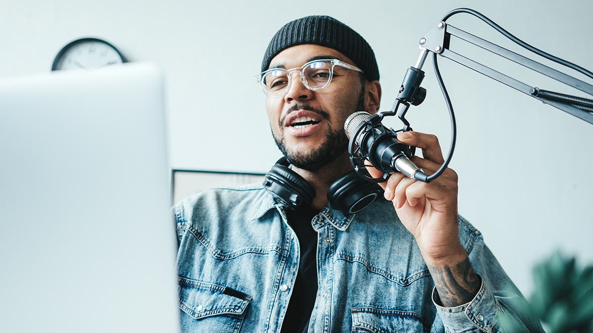 Handsome mixed race man streaming his audio podcast at small and cozy home broadcast studio