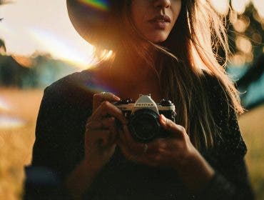 a female photographer holding a camera in a field