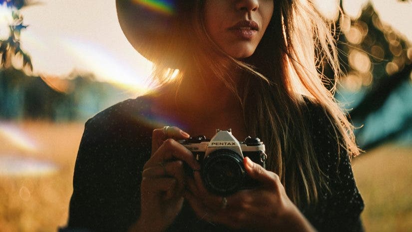 a female photographer holding a camera in a field