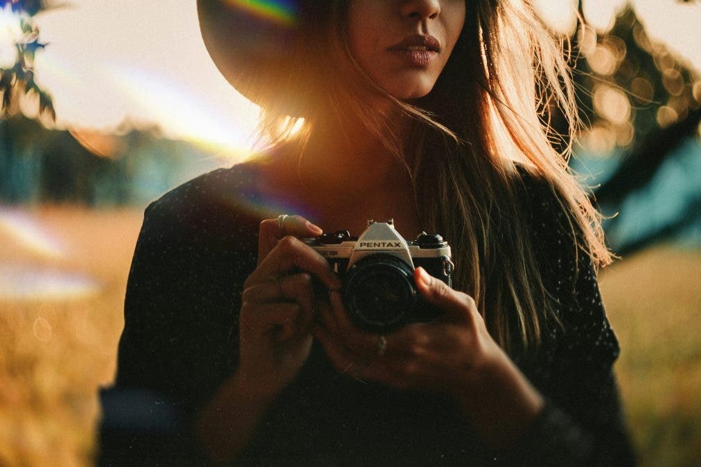 a female photographer holding a camera in a field