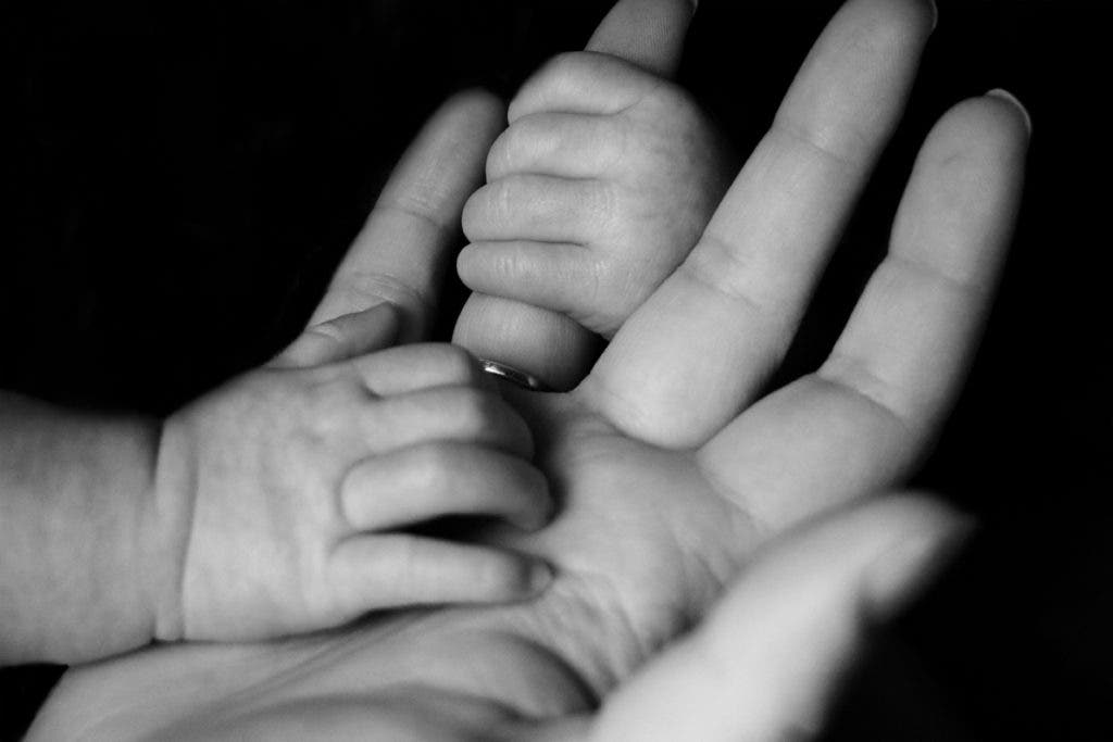 A Mother's Day macro shot of a baby clutching their mother's hand.