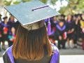 a girl wearing a graduation cap and toga with her back to the camera