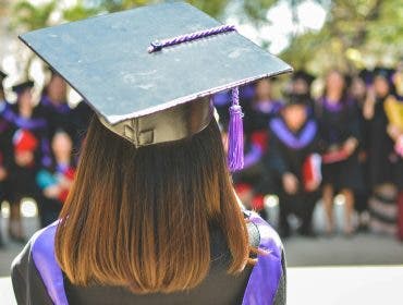 a girl wearing a graduation cap and toga with her back to the camera