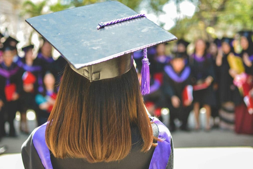a girl wearing a graduation cap and toga with her back to the camera