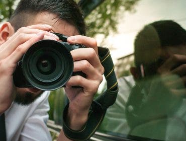 Young photographer with camera, isolated on white