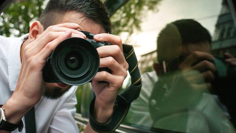 Young photographer with camera, isolated on white