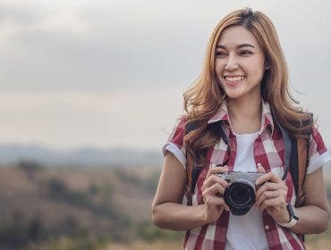 A tourist woman taking a photo with her mirrorless camera in nature