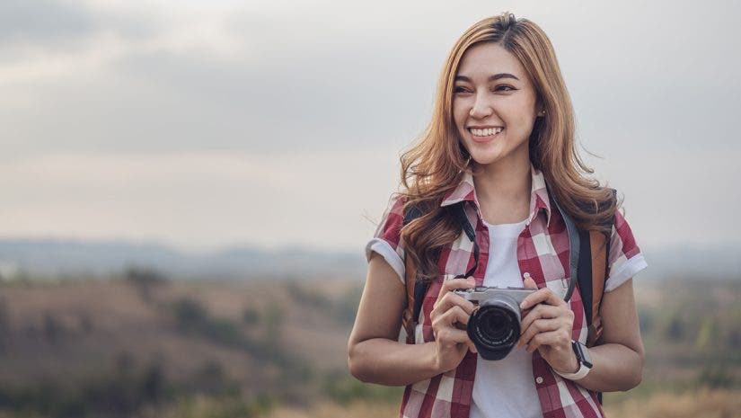 A tourist woman taking a photo with her mirrorless camera in nature
