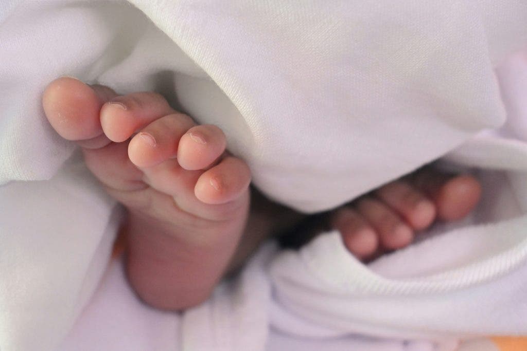 a closeup of a newborn baby's foot under a blanket