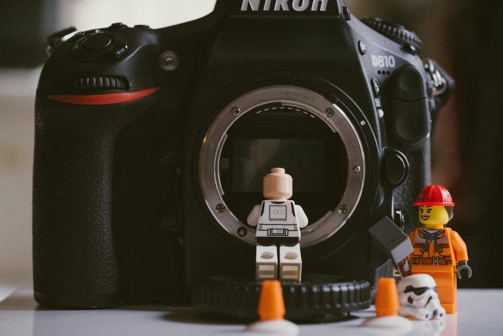 lego figures crawling out of a mirrorless camera