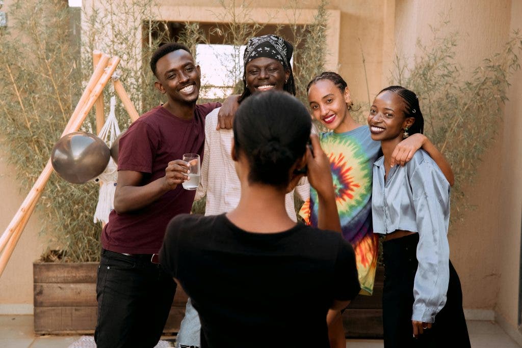 a photographer taking a picture of a group of black teenagers smiling
