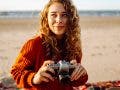 A young woman traveler is taking pictures of nature on a retro camera - a photography trend in 2025