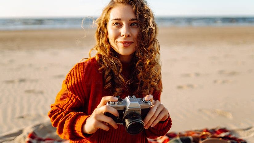 A young woman traveler is taking pictures of nature on a retro camera - a photography trend in 2025