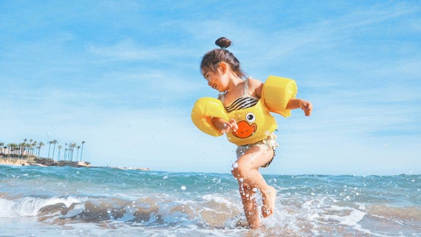 a photograph of kid splashing around in the ocean in the summer