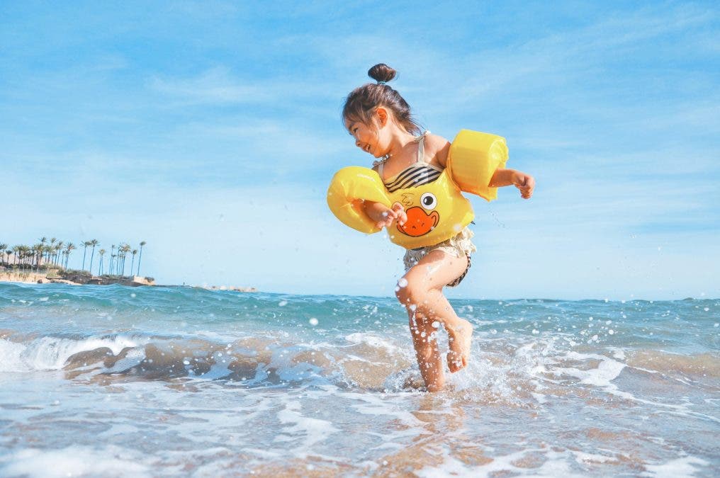 a photograph of kid splashing around in the ocean in the summer
