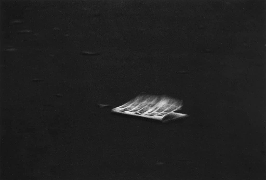 Windblown Headline on a Dark Pavement, NYC, 1956