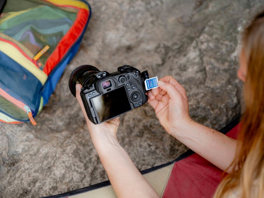 a woman holds an SD card and her camera