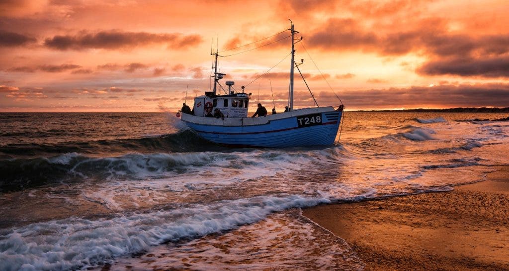 golden hour photo of a fishing boat near the shoreline
