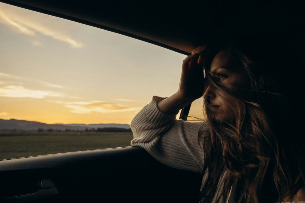 cinematic photograph of a woman in white and black striped long sleeve shirt sitting on car seat during daytime