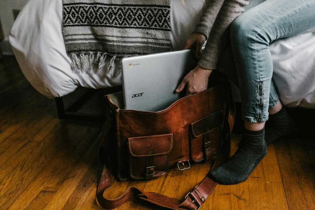 a student places his laptop in a satchel bag
