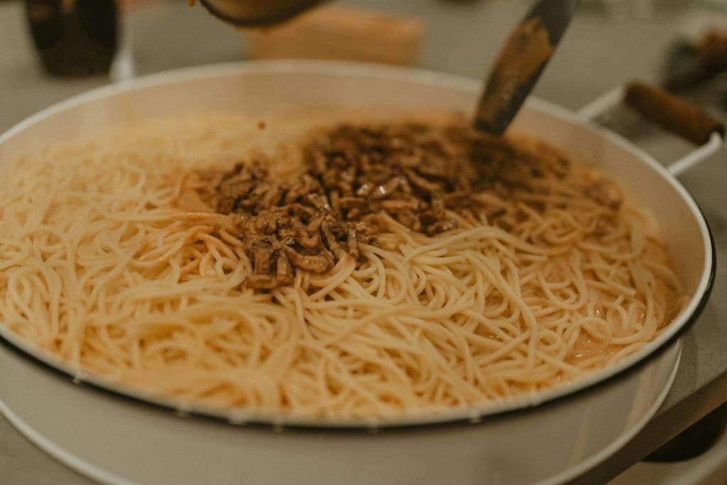 Close-up shot of sauce being poured over pasta
