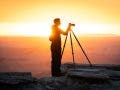 a photographer being backlit by a sunset