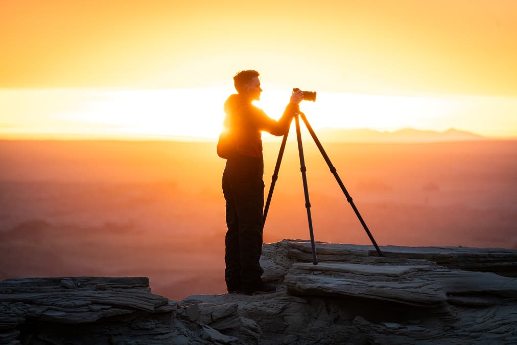 a photographer being backlit by a sunset