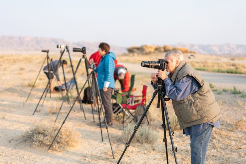 photographer peeks into her camera while photographers behind her set up their photography equipment